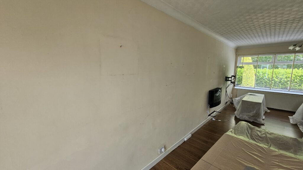 Interior room before painting, showing original wall condition and furniture prepared for decorating