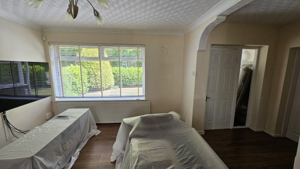 Room prepared for interior painting with furniture covered before decorating work began