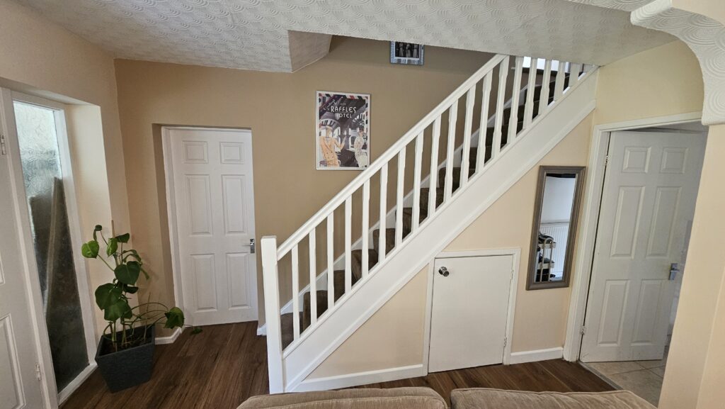 Finished staircase and hallway area with fresh paintwork, white balustrade and wood-effect flooring