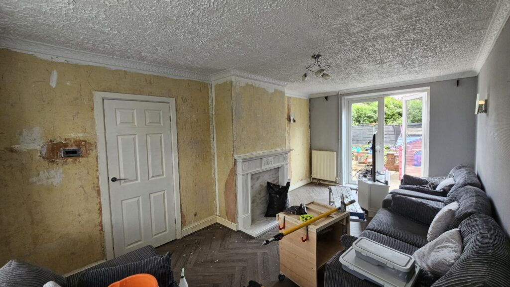 Living room before renovation with wallpaper removed and walls prepared for decorating