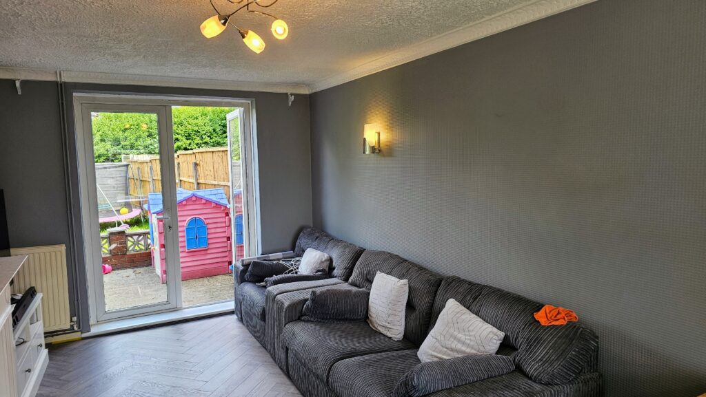 Finished living room with dark painted wall, large sofa and patio doors