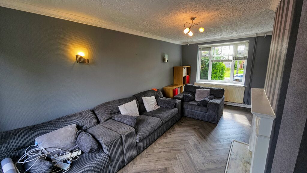 Finished living room with striped feature wallpaper, dark painted walls and herringbone-style flooring