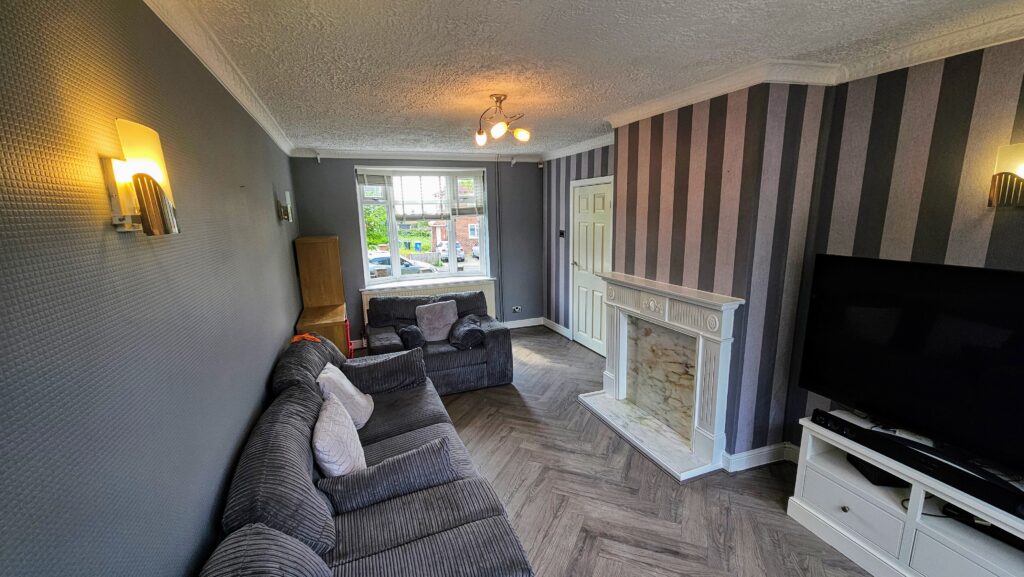 Finished living room with striped feature wallpaper, dark painted walls, fireplace and herringbone-style flooring