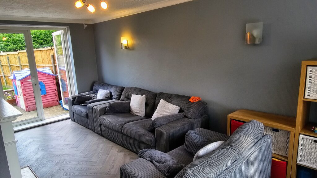 Living room with dark painted feature wall and herringbone-style flooring