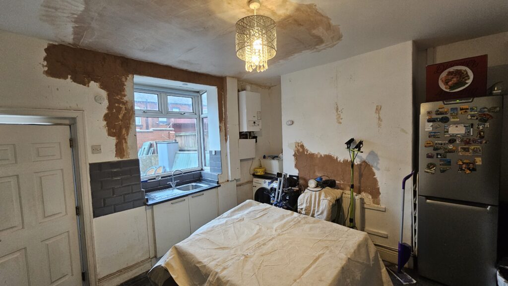 Kitchen during refurbishment showing damaged walls and ceiling before plastering and painting