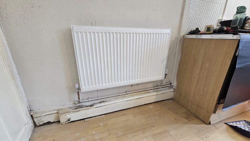 Preparation work on damaged skirting board and exposed radiator pipework before boxing installation