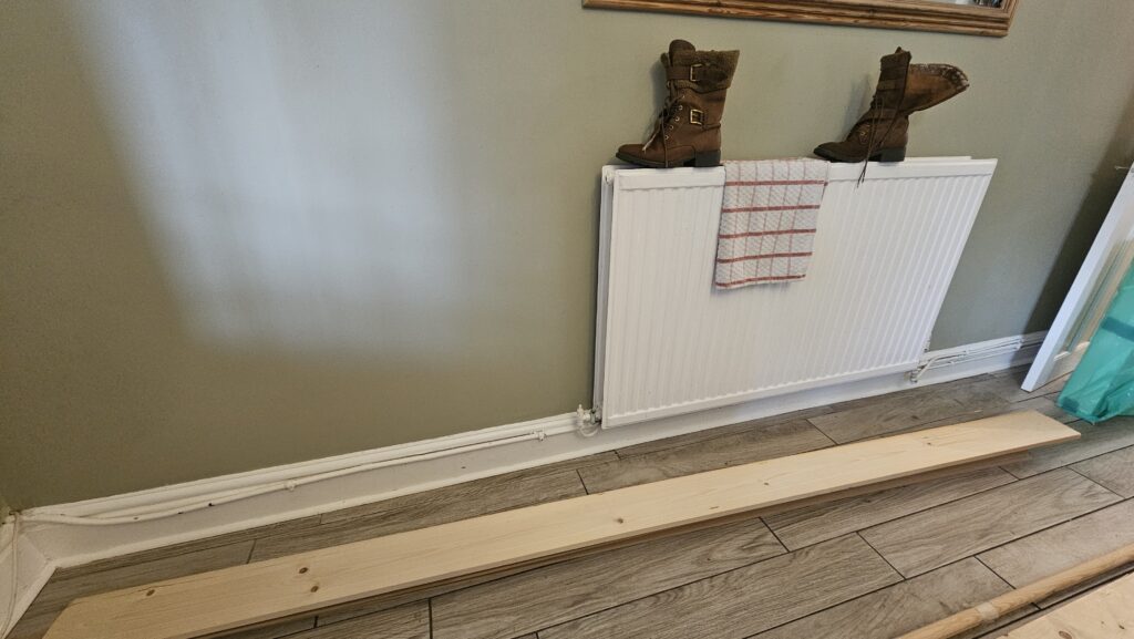 Radiator pipe boxing project in progress with timber prepared for fitting beneath a wall-mounted radiator