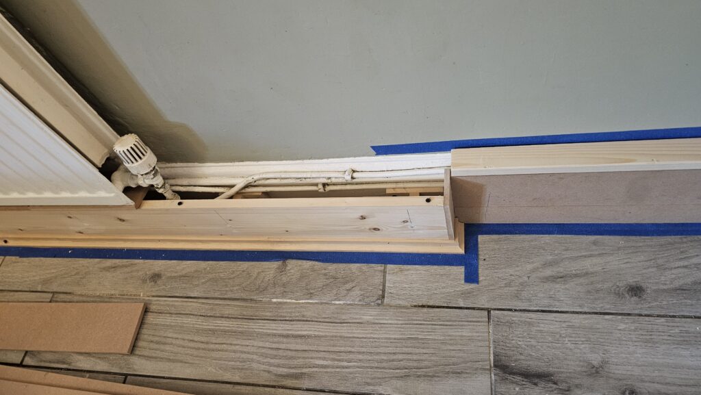 Custom timber framework for radiator pipe boxing being fitted along the skirting line