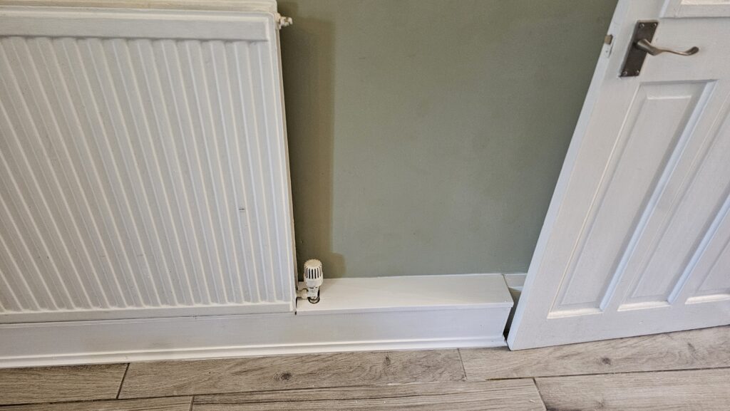 Finished radiator pipe boxing detail with clean skirting finish beside a doorway