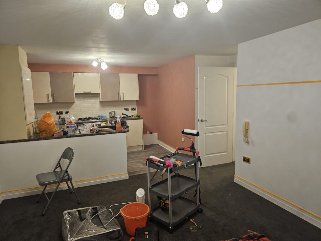 Living room and kitchen painting project in progress with masking and preparation work