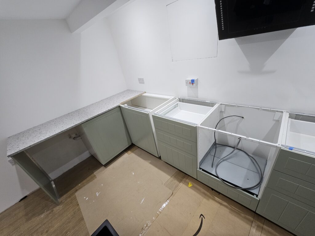 Kitchen units prepared for worktop fitting with sink and hob areas awaiting installation