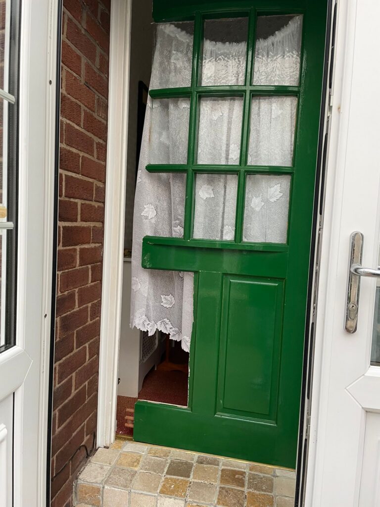 Old glazed door before replacement, showing the original condition and damaged lower panel
