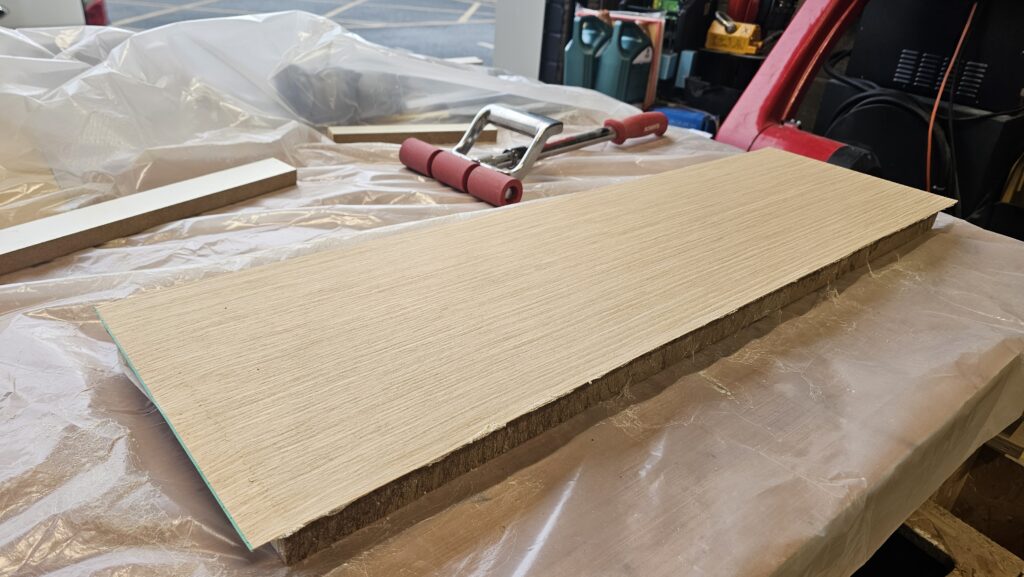 Wood veneer being applied to a modified shelf board to create a custom finish for the kitchen shelving.