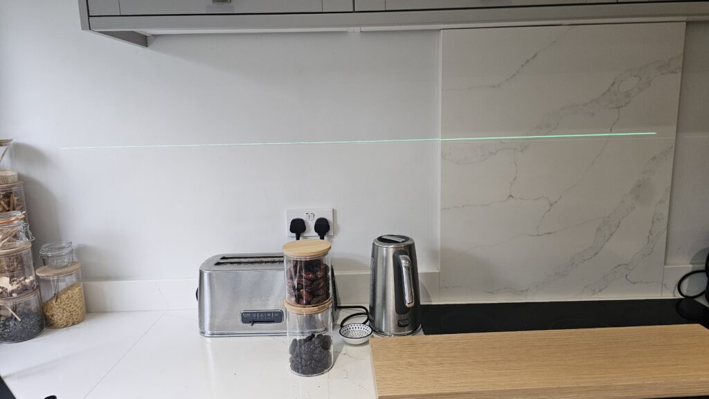 Laser level used to determine the ideal height and alignment for the custom kitchen shelves.
