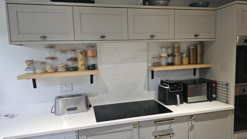 Custom wood veneer kitchen shelves reinforced with black metal brackets and holding glass storage jars.