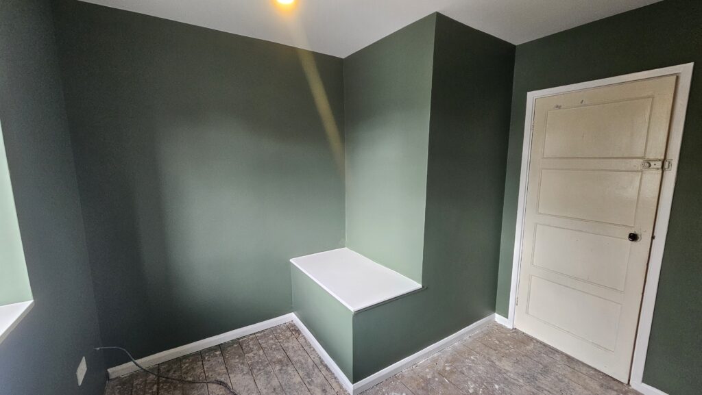 Finished box room decoration with sage green walls and custom MDF shelf in Manchester