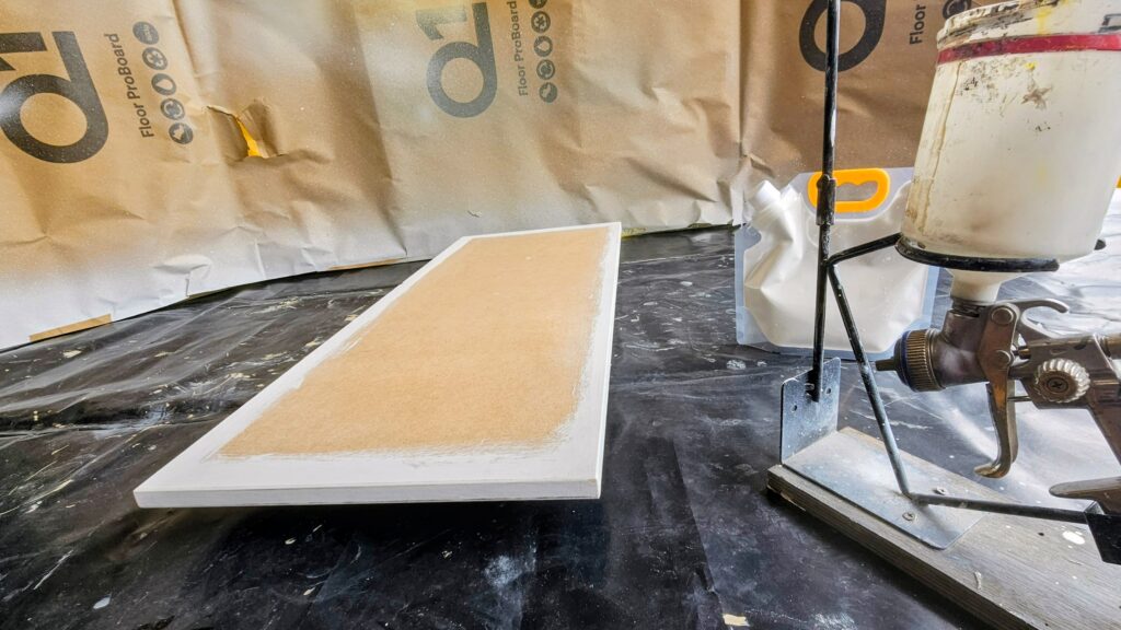 Custom MDF boiler cupboard door being spray-painted in a workshop before installation in a kitchen in Glossop.