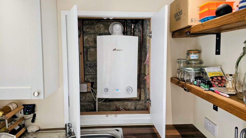 Custom push-open boiler cupboard doors opened to reveal the boiler and service access behind.