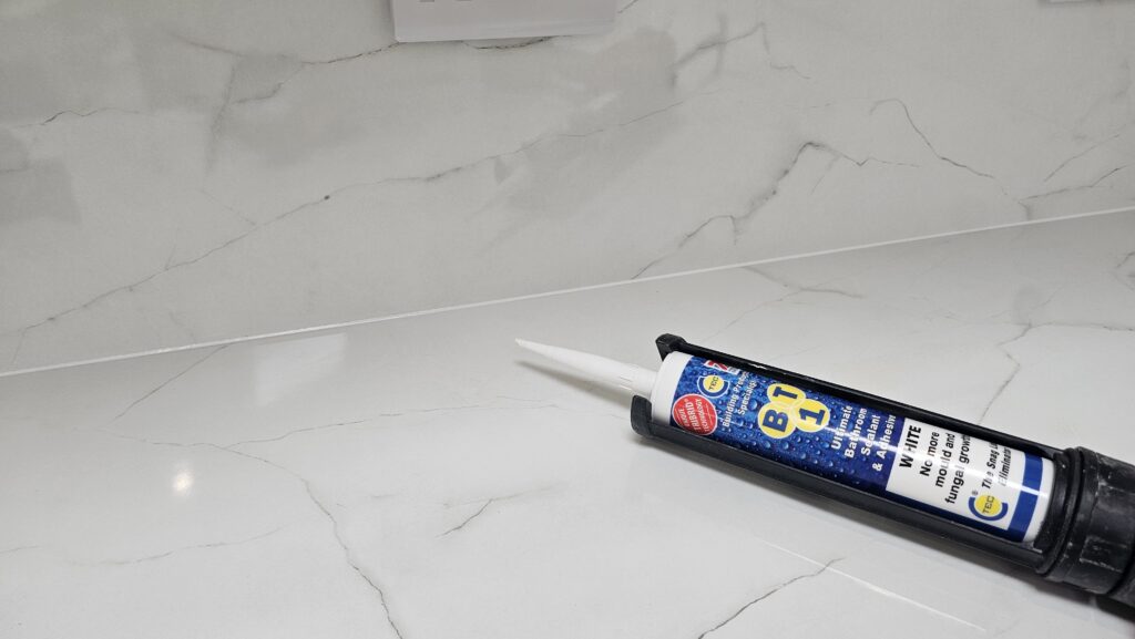 Applying waterproof sealant to the joint between the laminate worktop and matching upstand for a durable, watertight finish