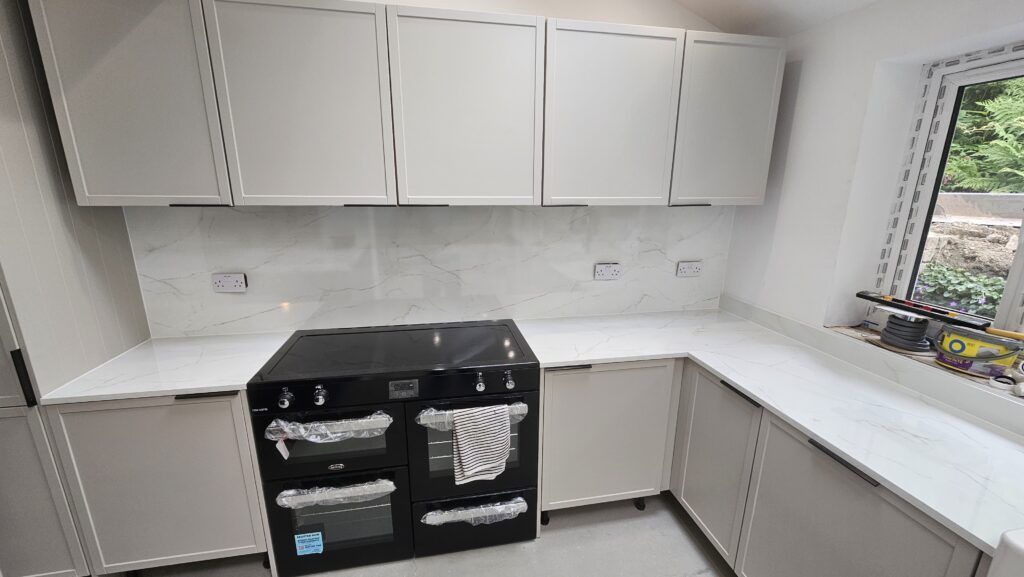 Completed installation of marble-effect laminate worktops, splashback panels and matching upstands in a modern L-shaped kitchen