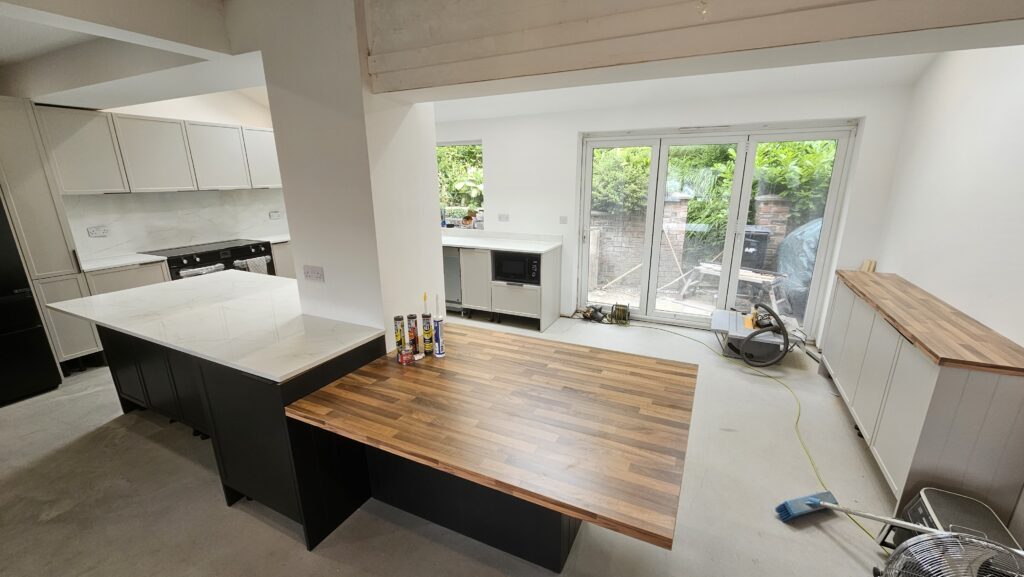 Completed bespoke kitchen featuring marble-effect worktops, splashbacks, integrated dining table and custom island