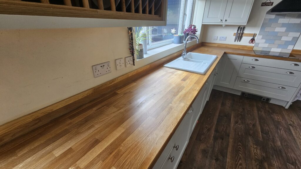 Wide-angle view of a restored solid oak kitchen worktop after sanding and refinishing with hard wax oil.