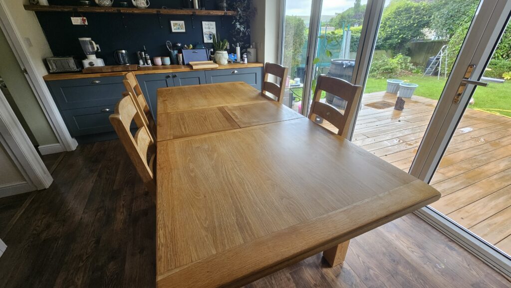 Wide-angle view of a restored solid oak dining table after sanding and refinishing with hard wax oil.