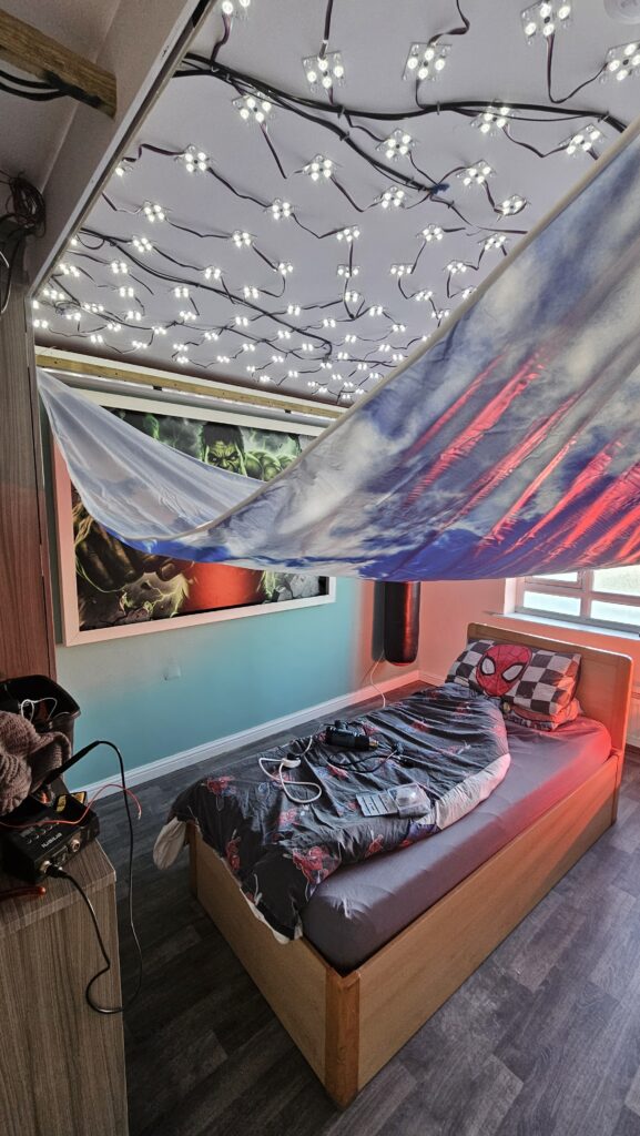 Installing the custom printed stretch ceiling over the LED lighting system in a bespoke Hulk themed bedroom