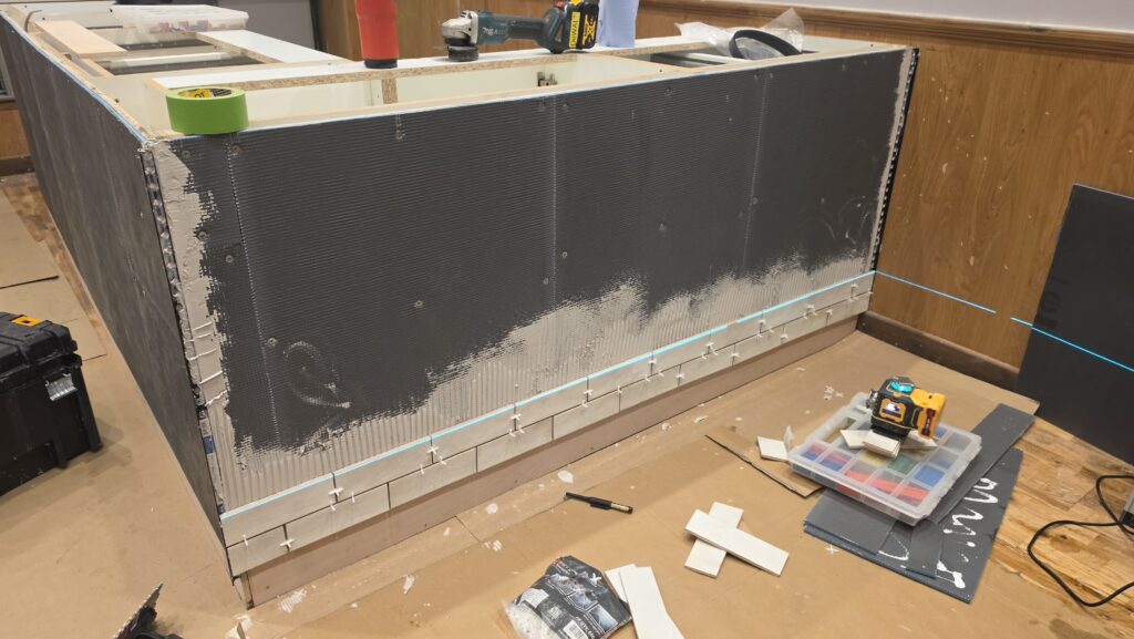Starting the café counter tiling with laser level and white brick tiles