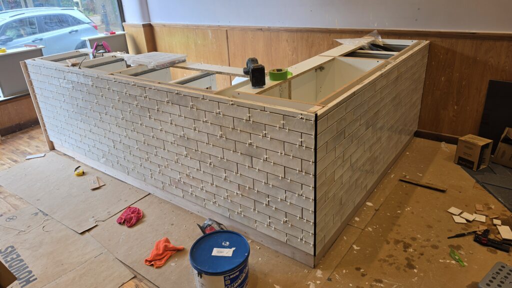 Second face of the bespoke café counter fully tiled in white brick tiles
